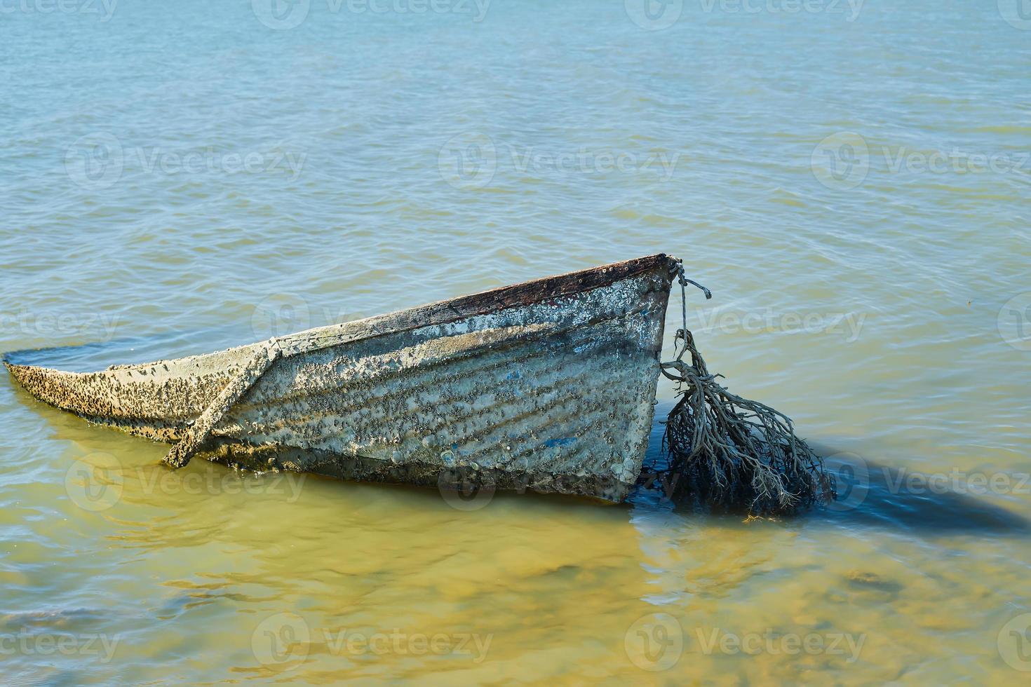 alt verlassen Boot, versunken in der Nähe von das Ufer, versunken oder verlassen Boot in der Nähe von das Meer. Wasser Verschmutzung, Umwelt Probleme und Müll Verschmutzung foto