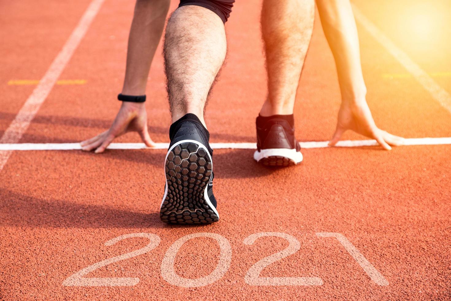 neues Jahr oder gerade Konzept beginnen. Nahaufnahme eines Athletenläufers, der zum Erfolg und zu neuen Errungenschaften auf dem Weg mit Inschrift 2021 läuft foto