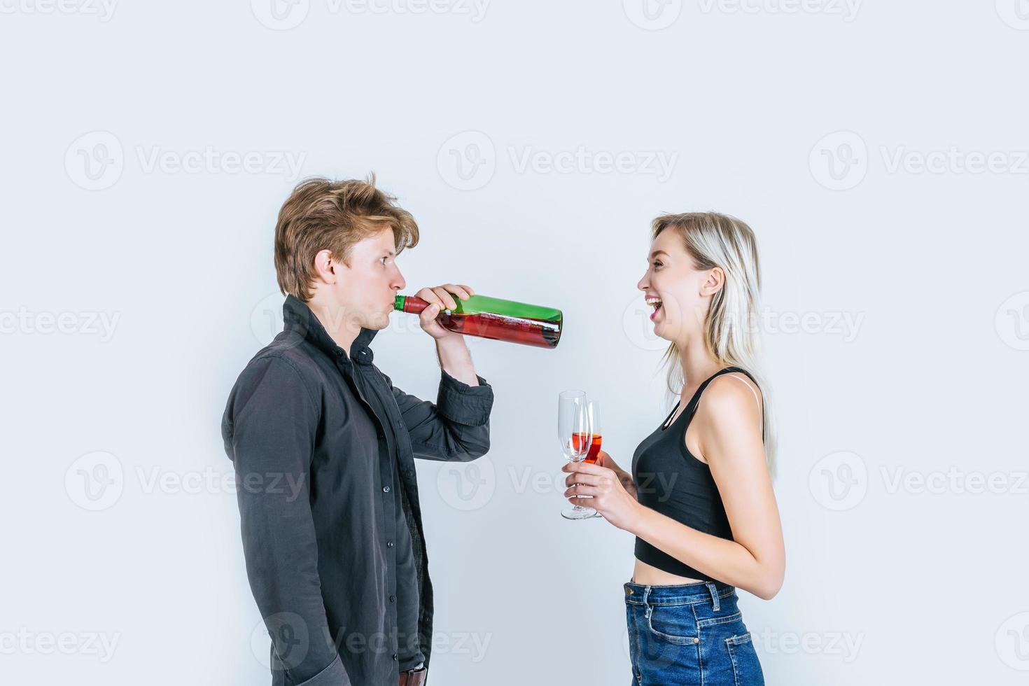 Porträt des glücklichen jungen Paares, das Wein im Studio trinkt foto