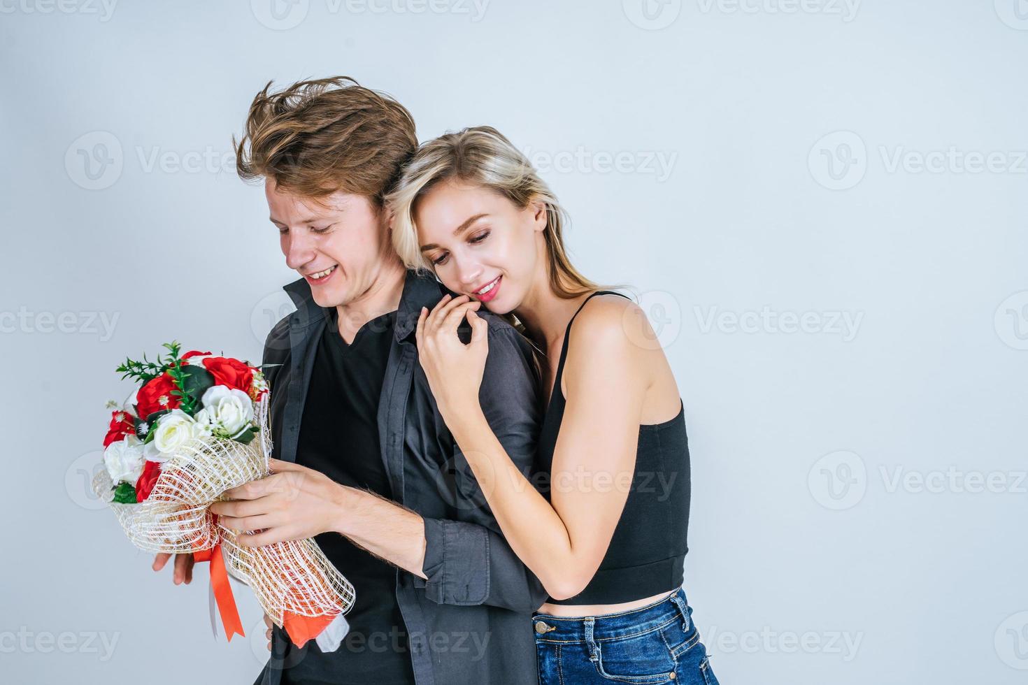 Porträt des glücklichen jungen Paares mit Blumen im Studio foto