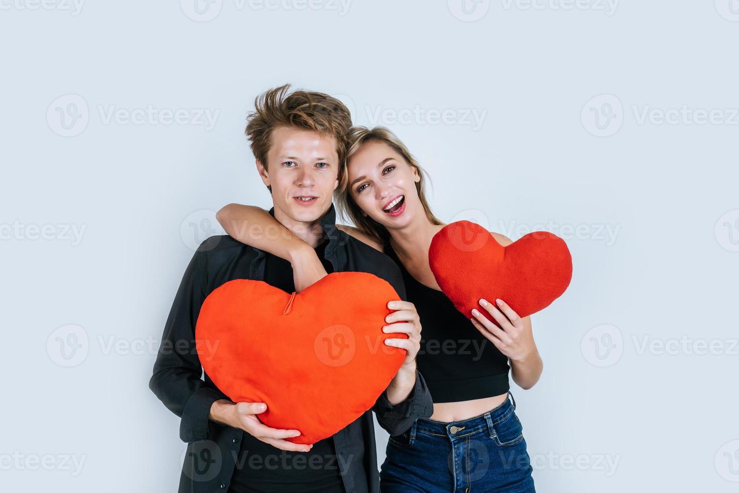 glückliches Paar, das zusammen liebt, ein rotes Herz haltend foto