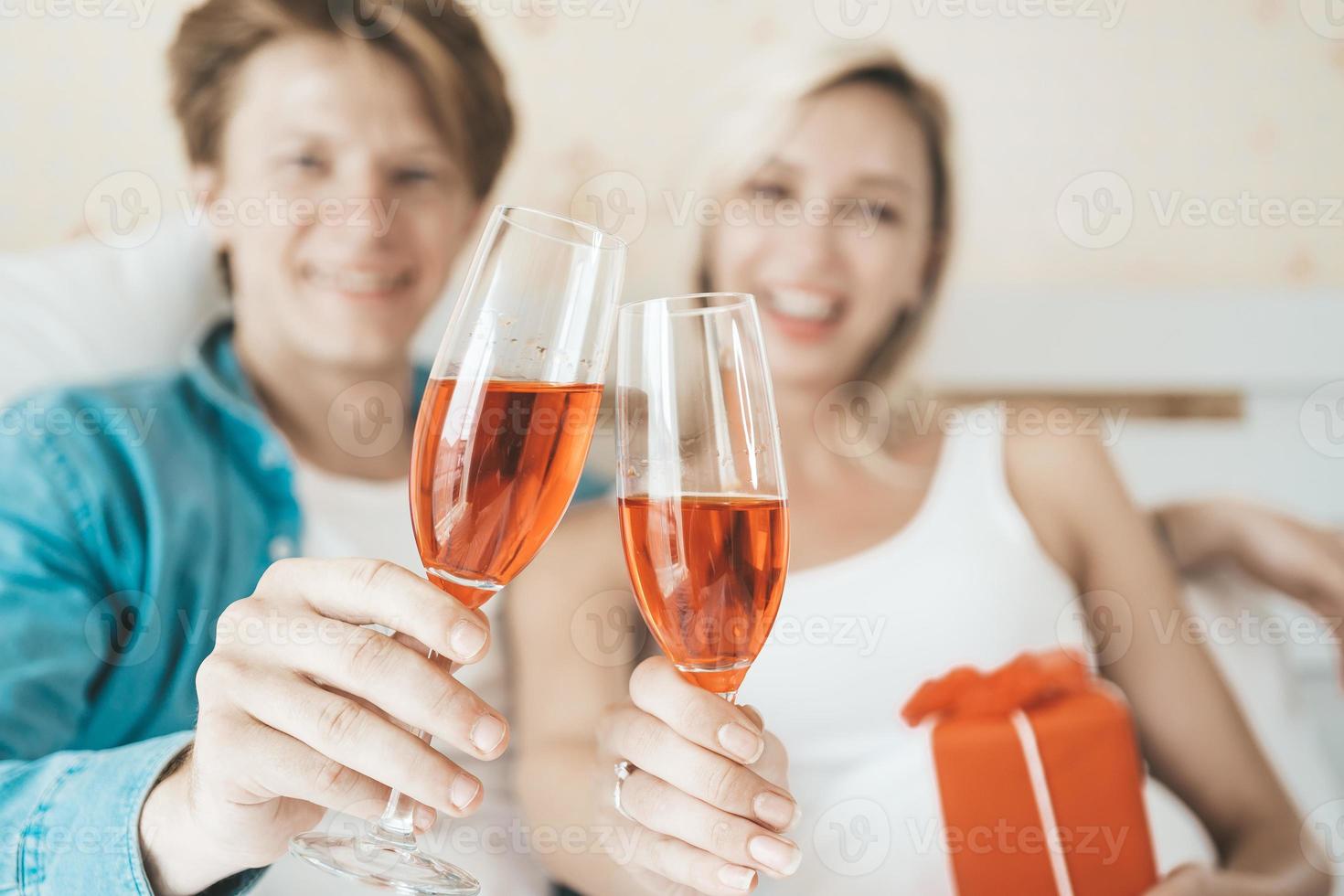 glückliches Paar, das Wein im Schlafzimmer trinkt foto