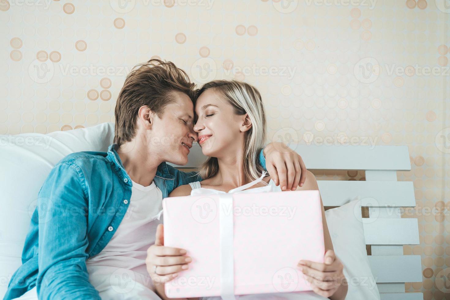 Freund überrascht seine Freundin mit Geschenkbox auf dem Bett foto