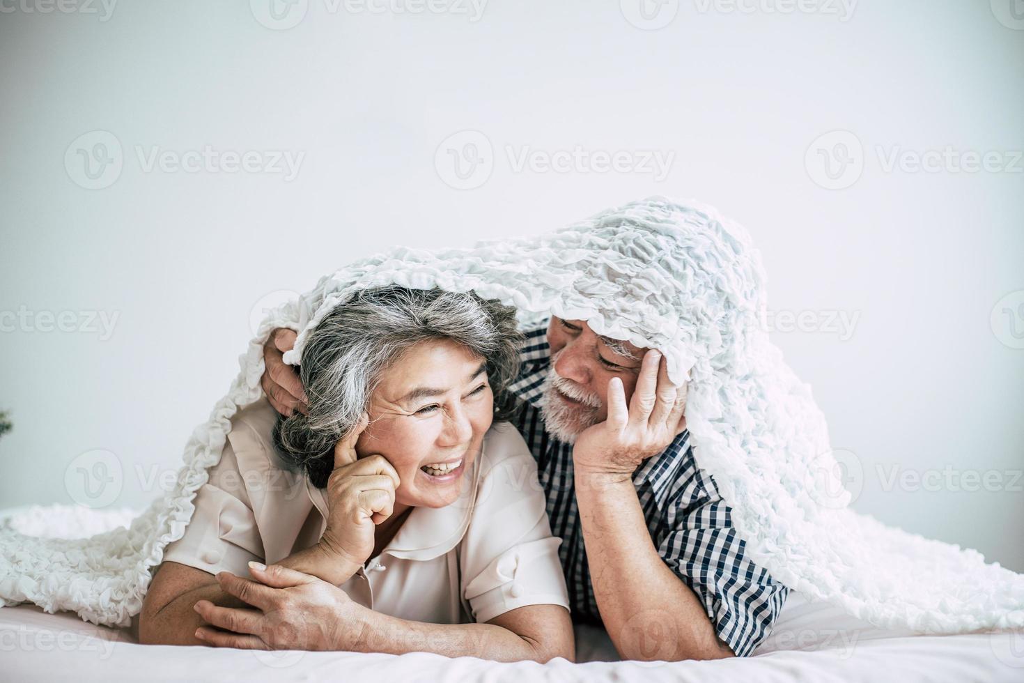 glückliches älteres Paar, das im Schlafzimmer lacht foto