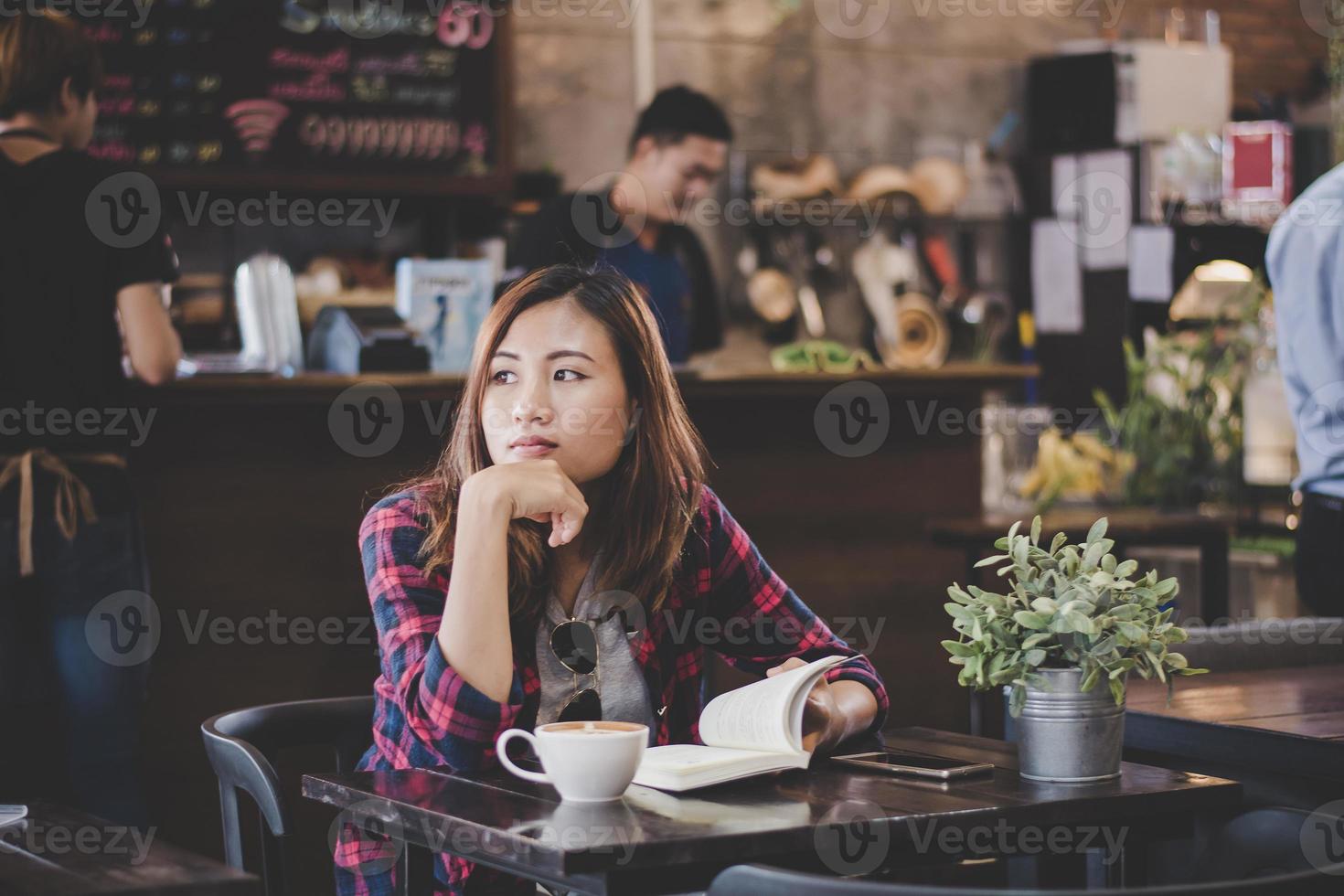 glückliche Geschäftsfrau, die ein Buch liest, während sie im Café entspannt foto