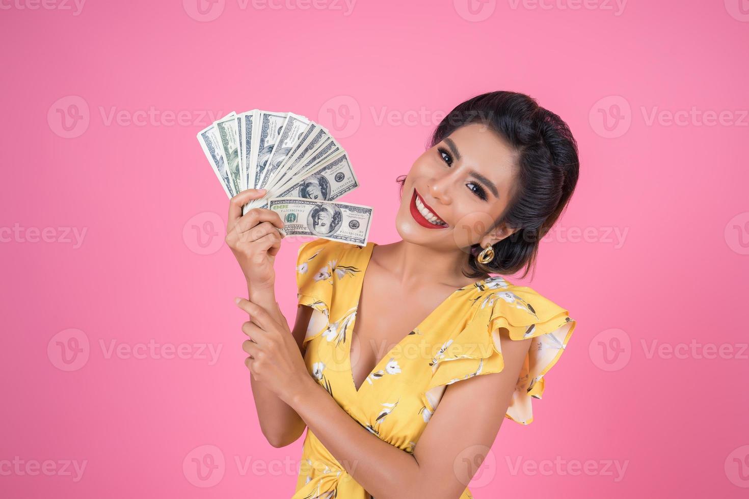 glückliche modische Frau, die Geld für das Einkaufen hält foto