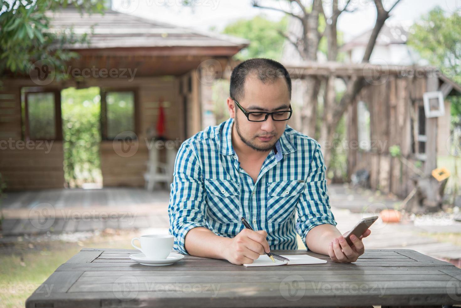 junger Geschäftsmann, der Smartphone während der Arbeit im Hausgarten verwendet foto