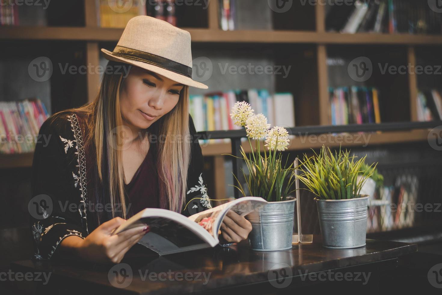 glückliche Geschäftsfrau, die ein Buch liest, während sie im Café entspannt foto