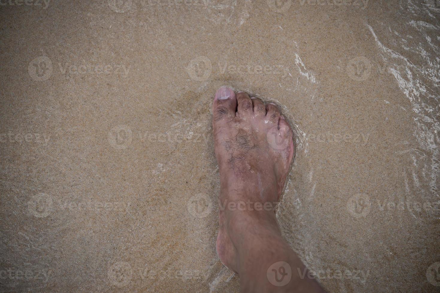 Männerfuß steht am Strand foto