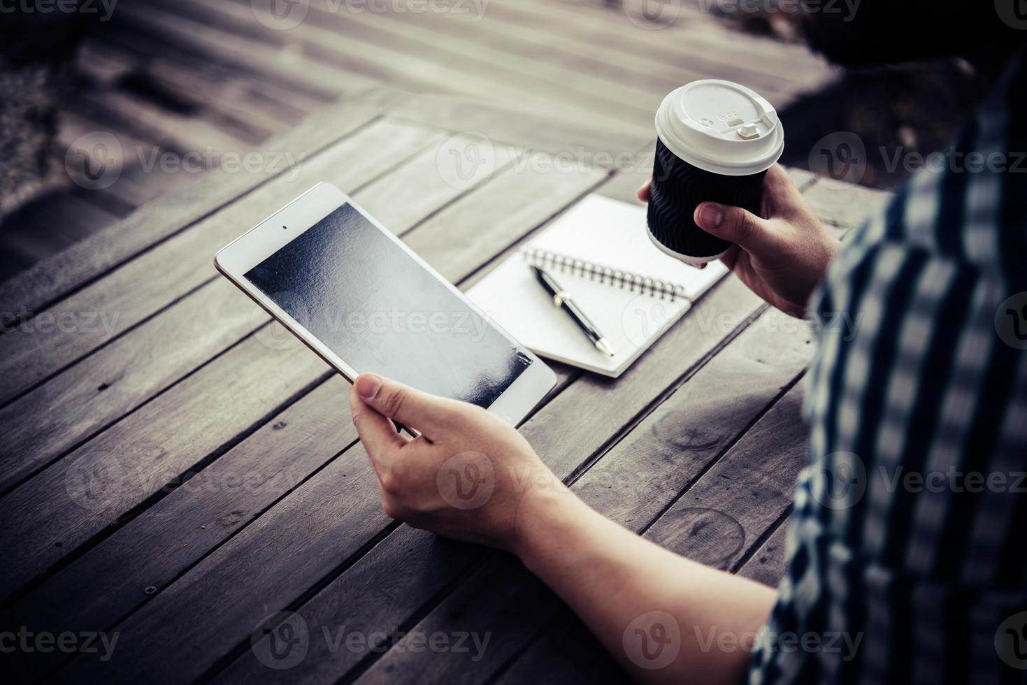 junger Mann, der digitale Tablette beim Kaffeetrinken im Hausgarten verwendet foto