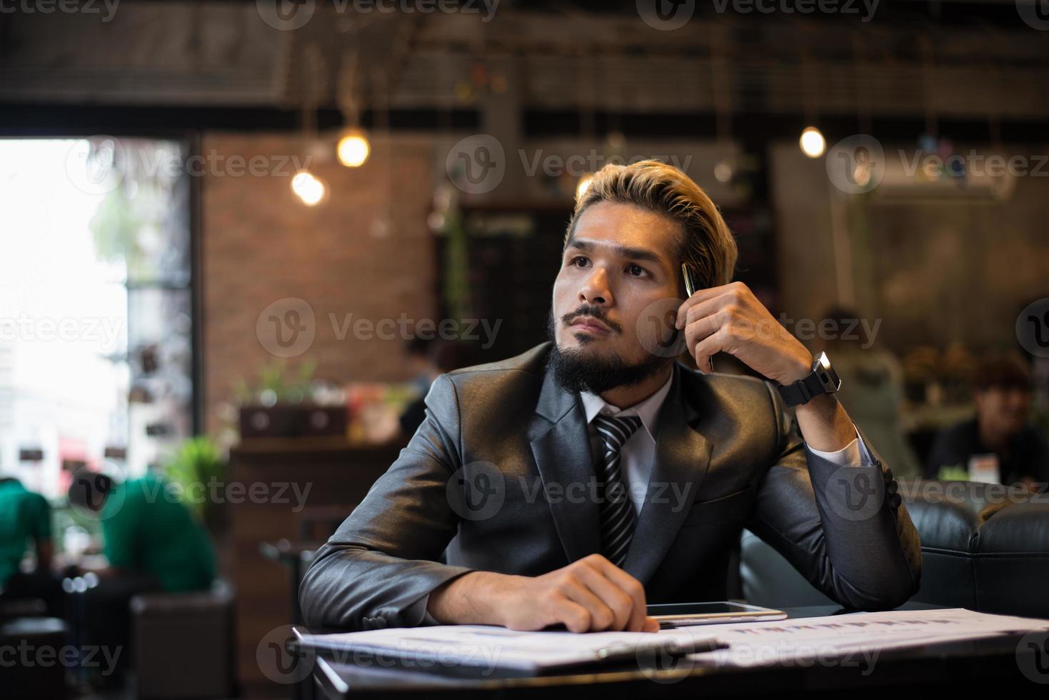 hübscher Geschäftsmann, der an Arbeit während der Arbeit im Café denkt foto