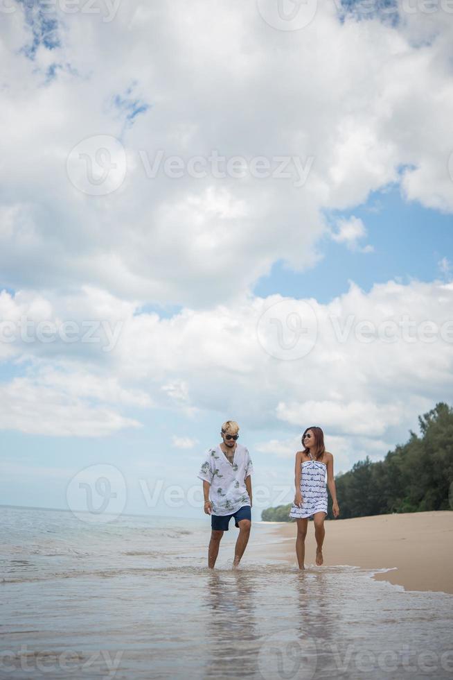 junges glückliches Paar, das lächelnd am Strand geht foto
