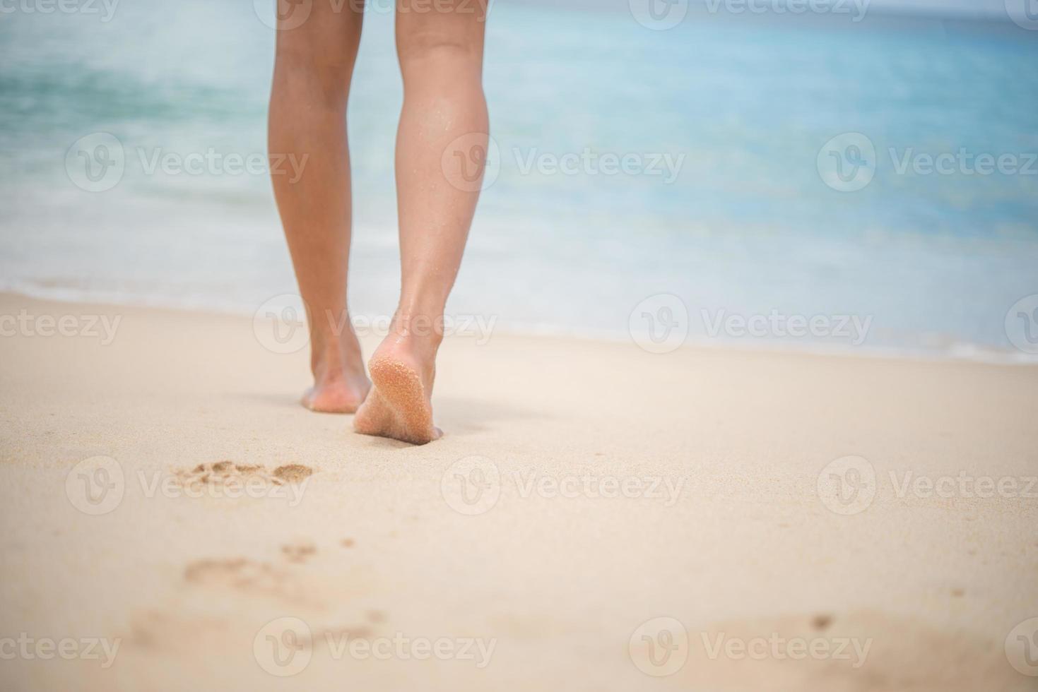 Nahaufnahme von Frauenbeinen, die am Strand gehen foto