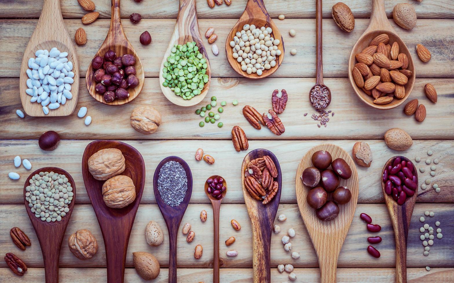 Hülsenfrüchte und Nüsse im Löffel auf hellem Holzhintergrund foto