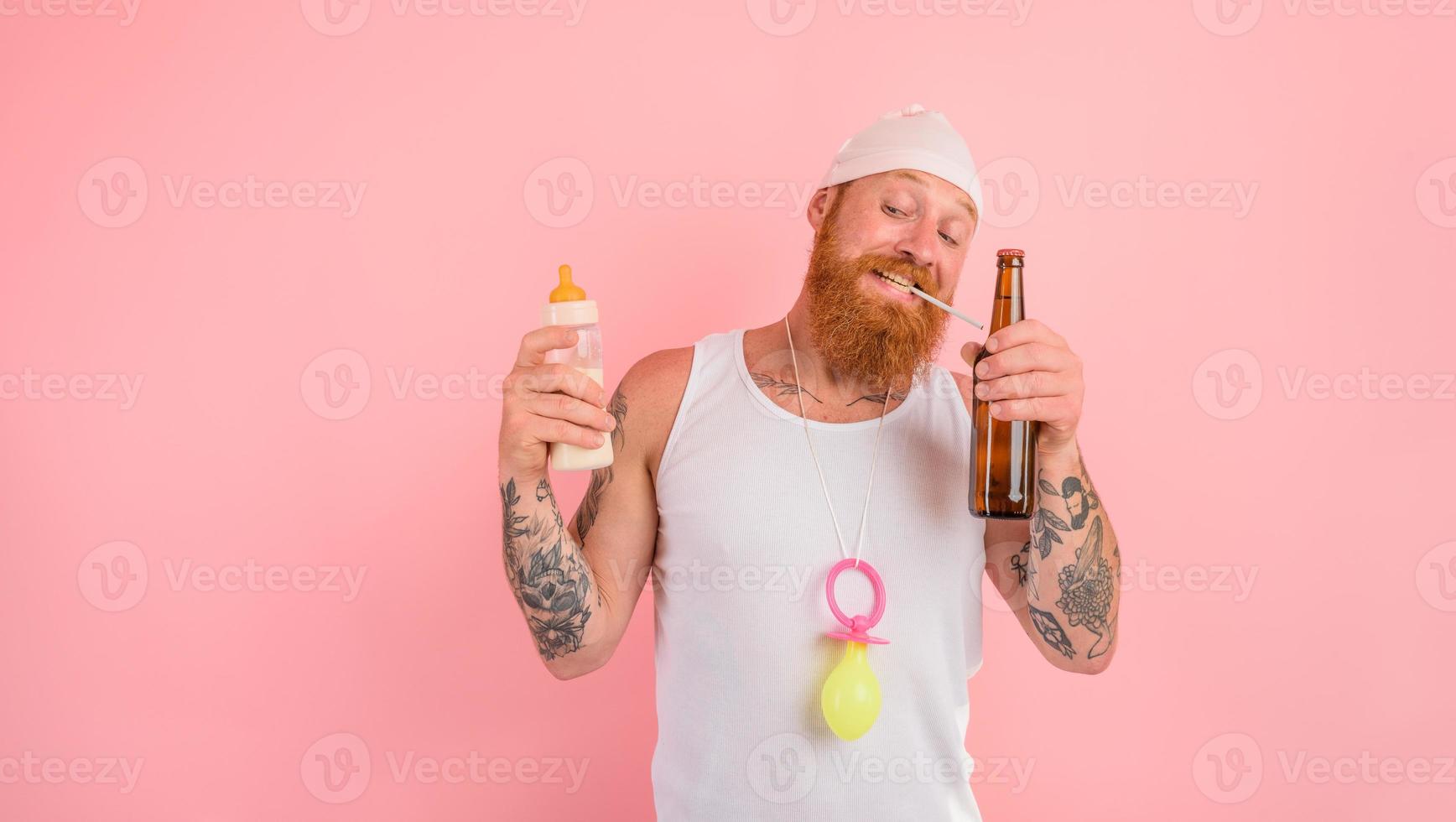 nachdenklich Mann mit Bart und Tätowierungen handelt mögen ein Neugeborene aber will ein Bier foto