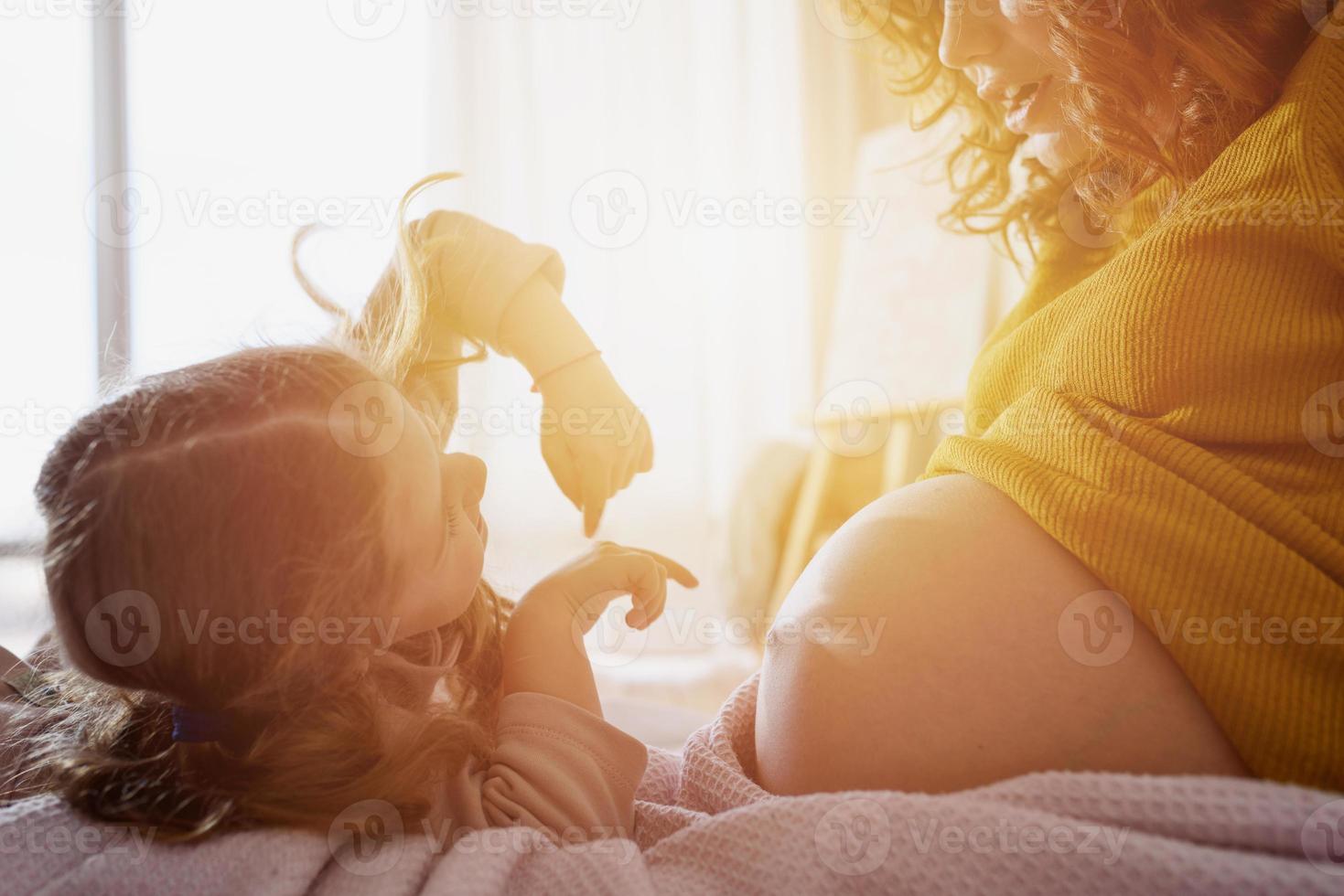 schwanger Mama Theaterstücke mit ihr Tochter. Konzept von Familie, Freude und Schwangerschaft foto