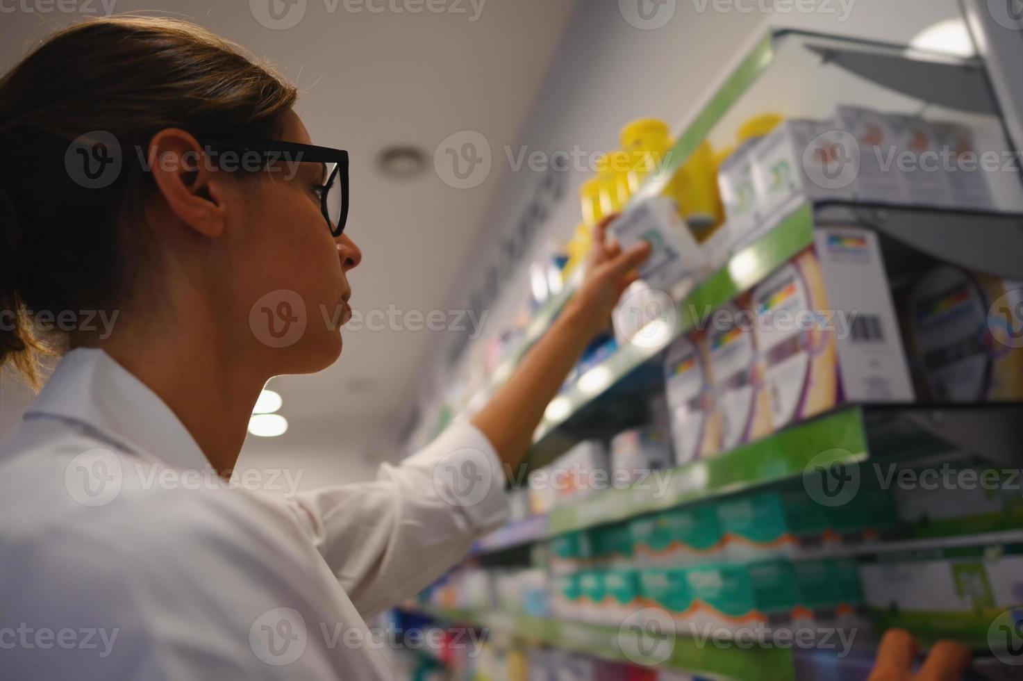 Frau Apotheker arrangiert Medizin auf das Regal im das Apotheke foto