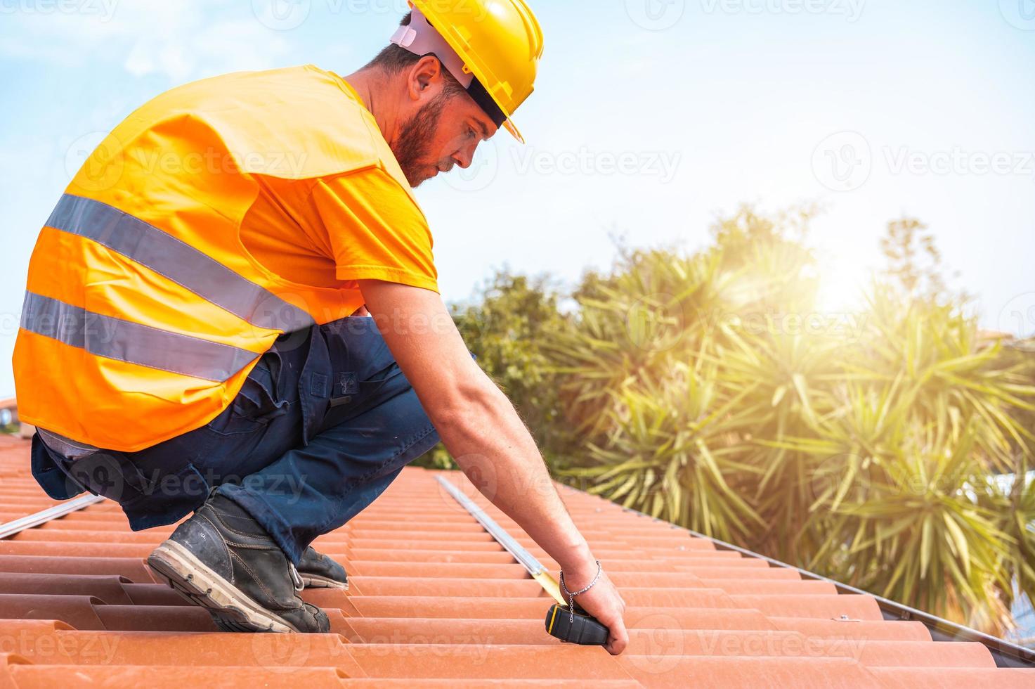 technisch Arbeiter nimmt Messungen auf das Dach von ein Haus foto