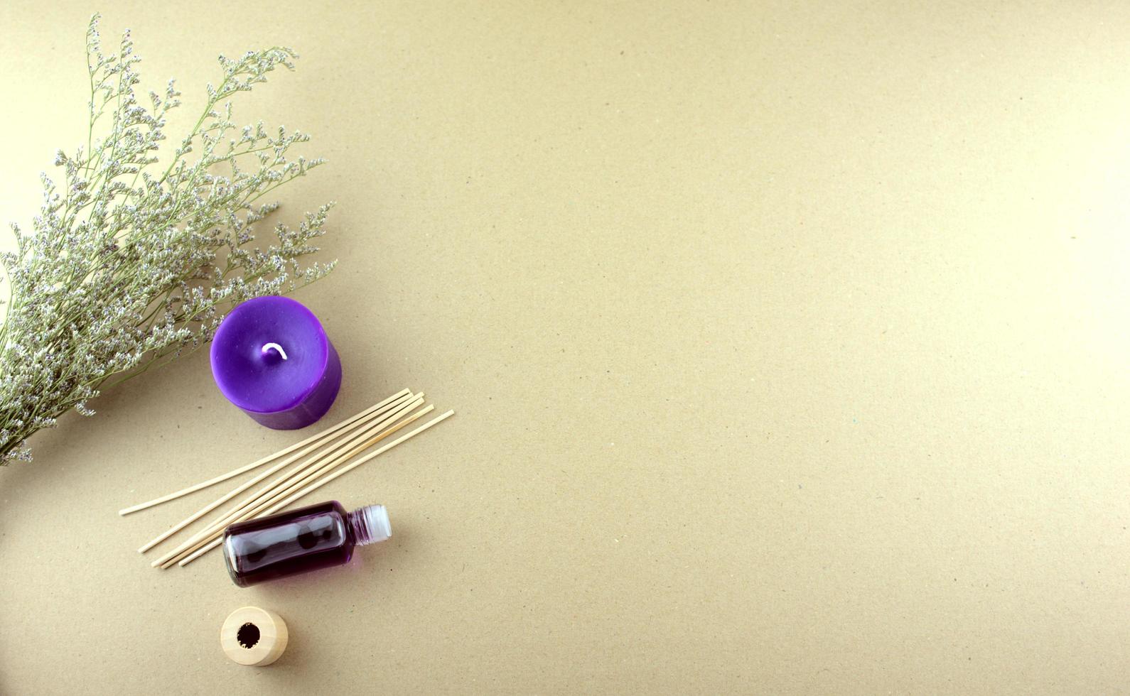 Lavendelduftöl in einer Flasche mit lila Kerzen, Holzstäbchen und trockenen Blumen lag flach auf einem Tisch foto