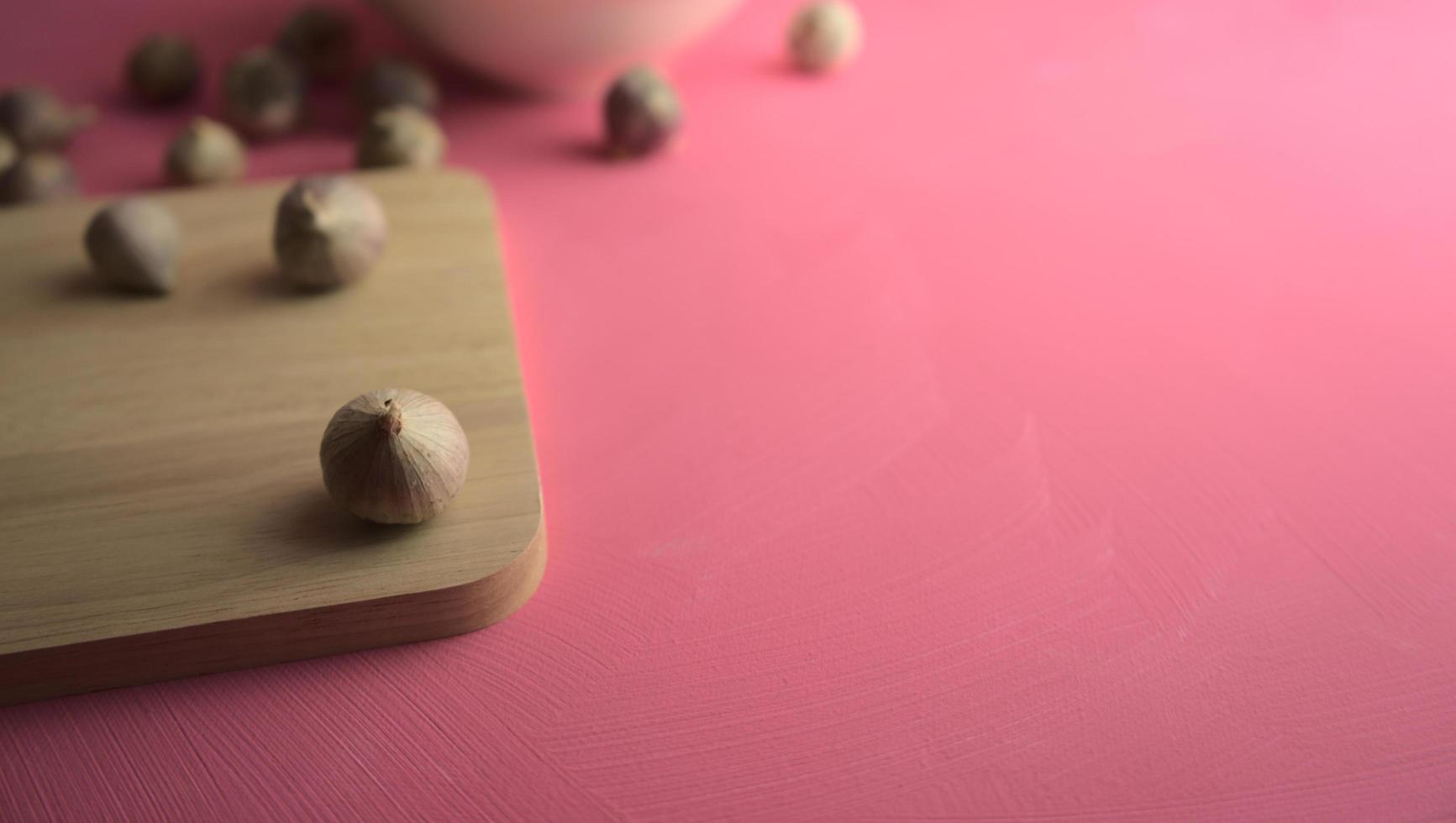 Knoblauch auf Schneidebrett auf rosa Leinwand Hintergrund foto