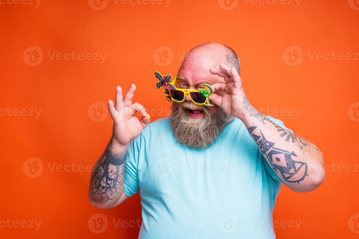 Fett glücklich Mann mit Bart, Tätowierungen und Sonnenbrille ist bereit zum das Sommer- foto