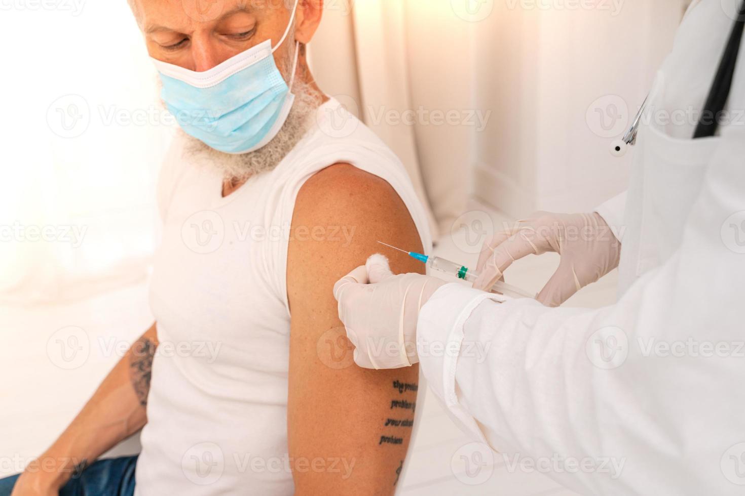 Arzt verwaltet das Impfstoff gegen covid-19 zu das geduldig mit das Spritze foto