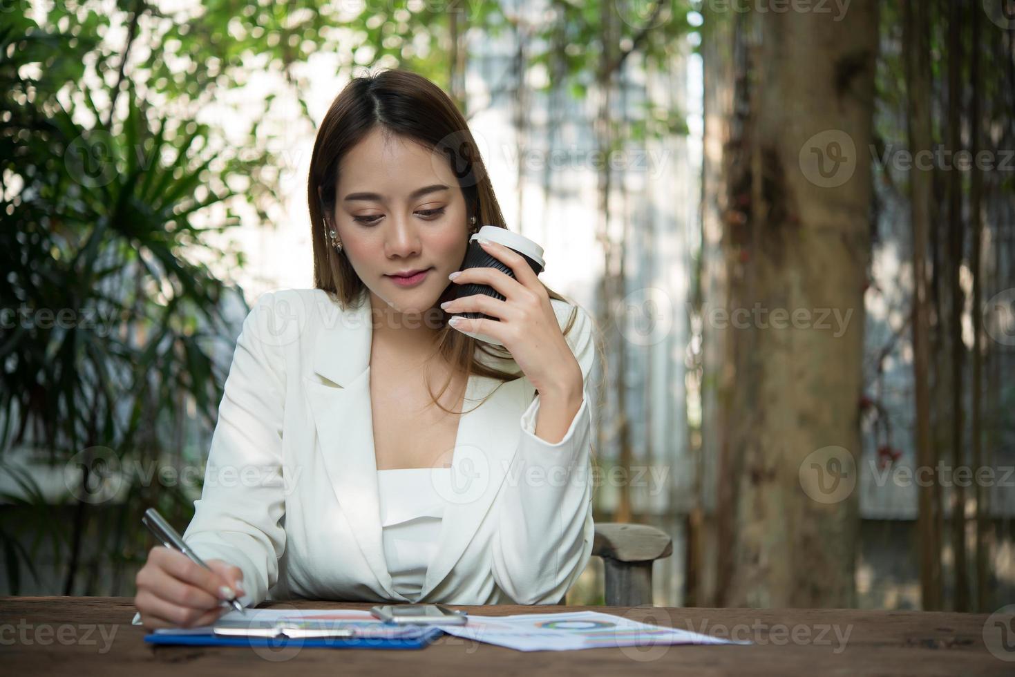 junge Geschäftsfrau, die in einem Büro sitzt und eine Tasse Kaffee trinkt foto