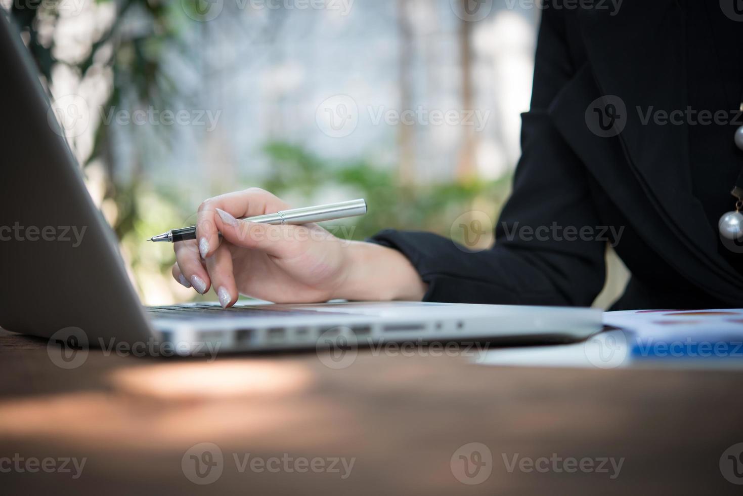 Frau arbeitet mit ihrem Laptop und Geschäftsbericht foto