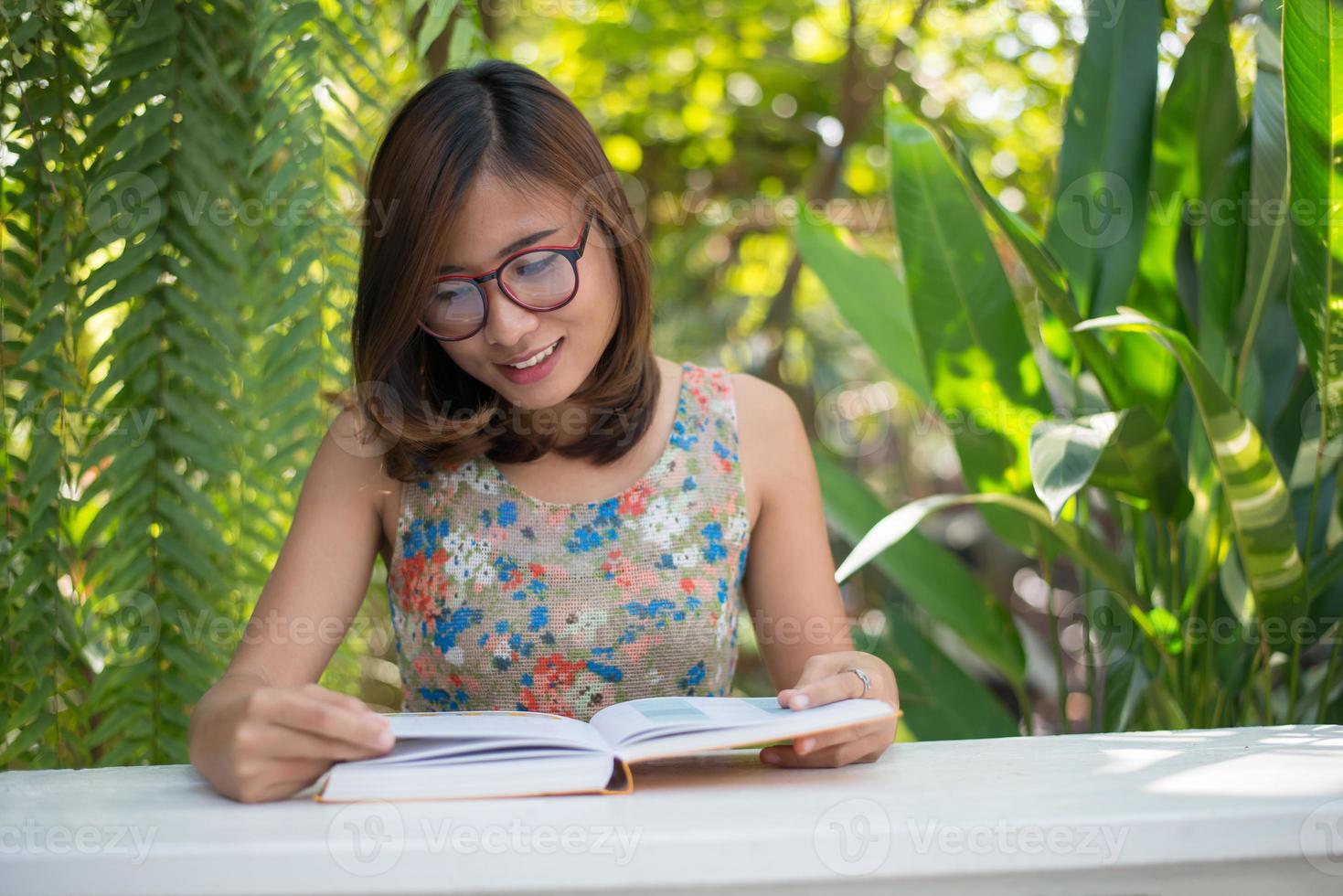 junge Hipsterfrau, die Bücher im Hausgarten mit Natur liest foto