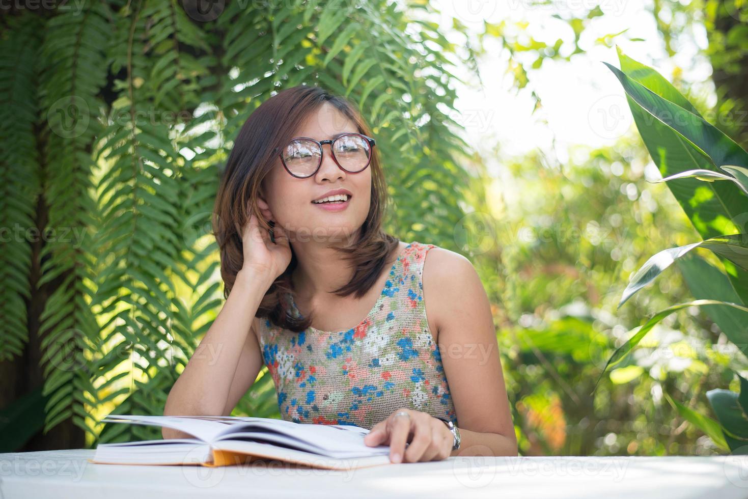 junge Hipsterfrau, die Bücher im Hausgarten mit Natur liest foto