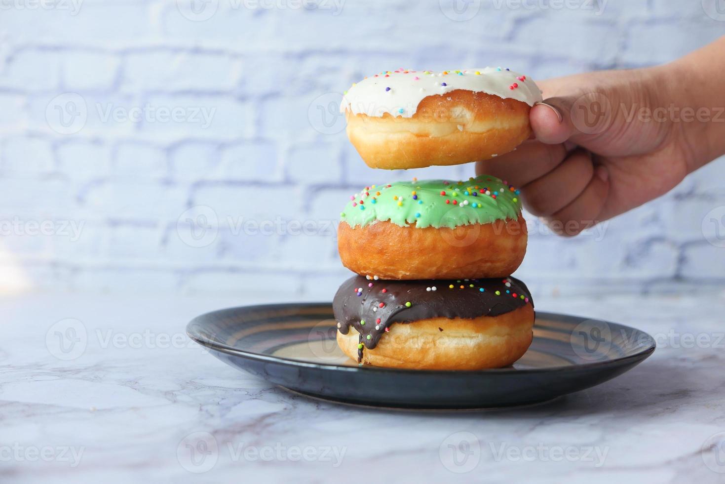 Hand mit frischen Donuts auf einem Teller foto
