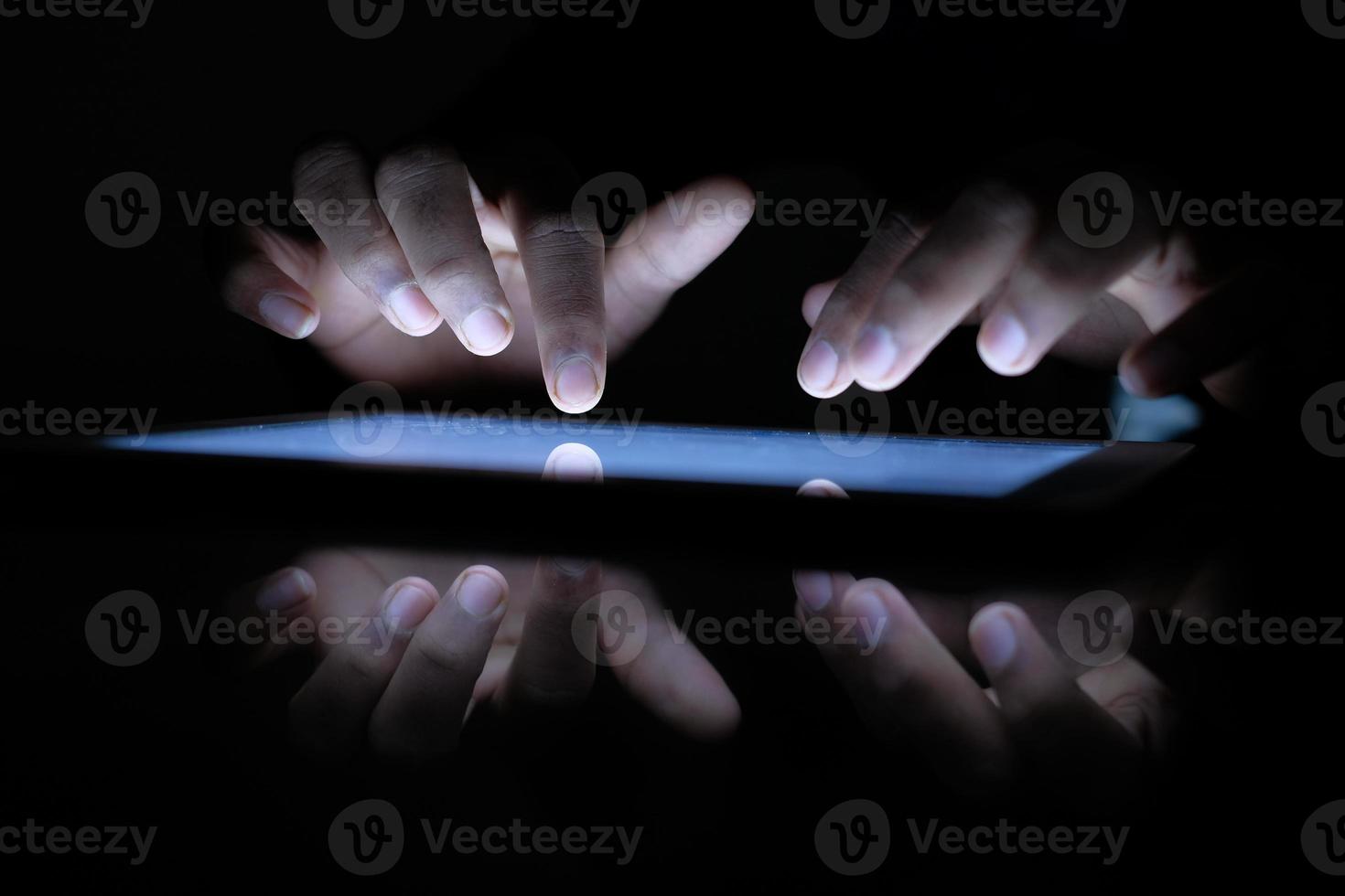 Nahaufnahme der Hände im Dunkeln tippen auf einem Tablet foto