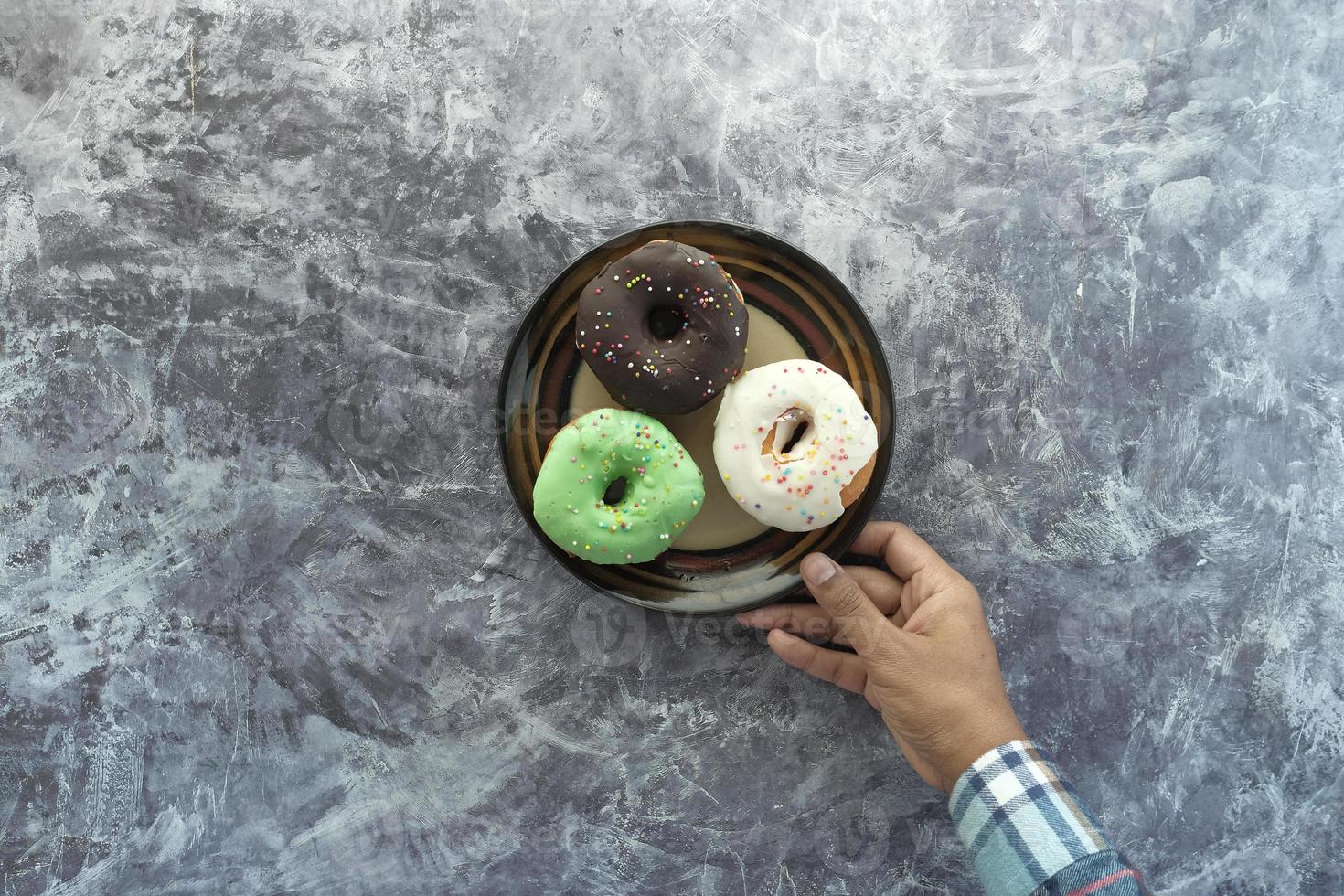 Hand hält einen Teller mit Donuts foto