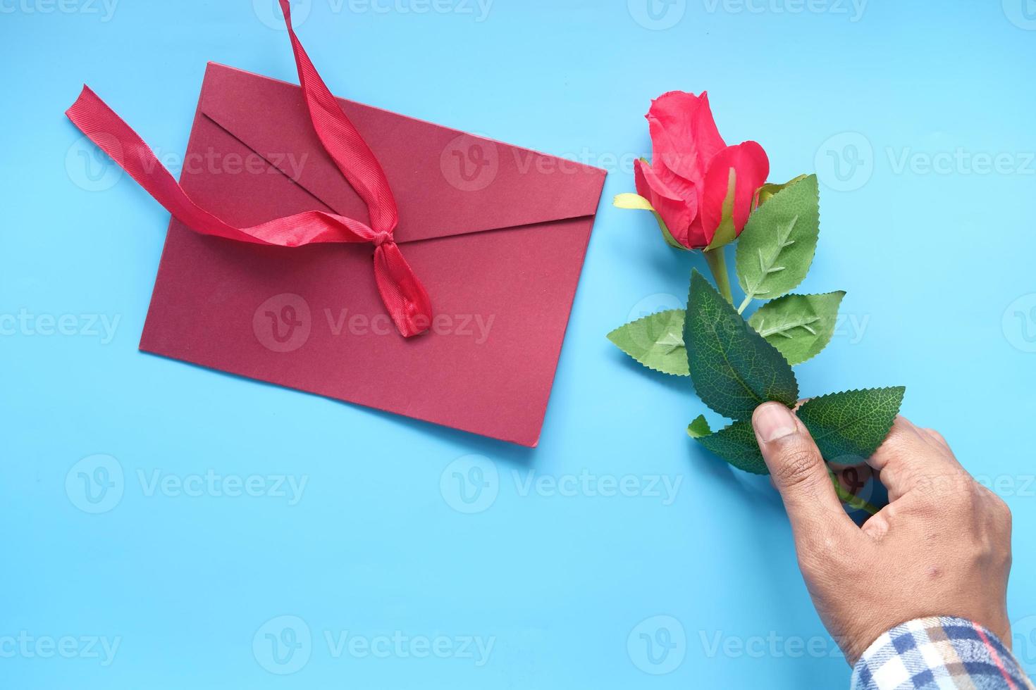 Mann hält eine Rose auf blauem Hintergrund foto