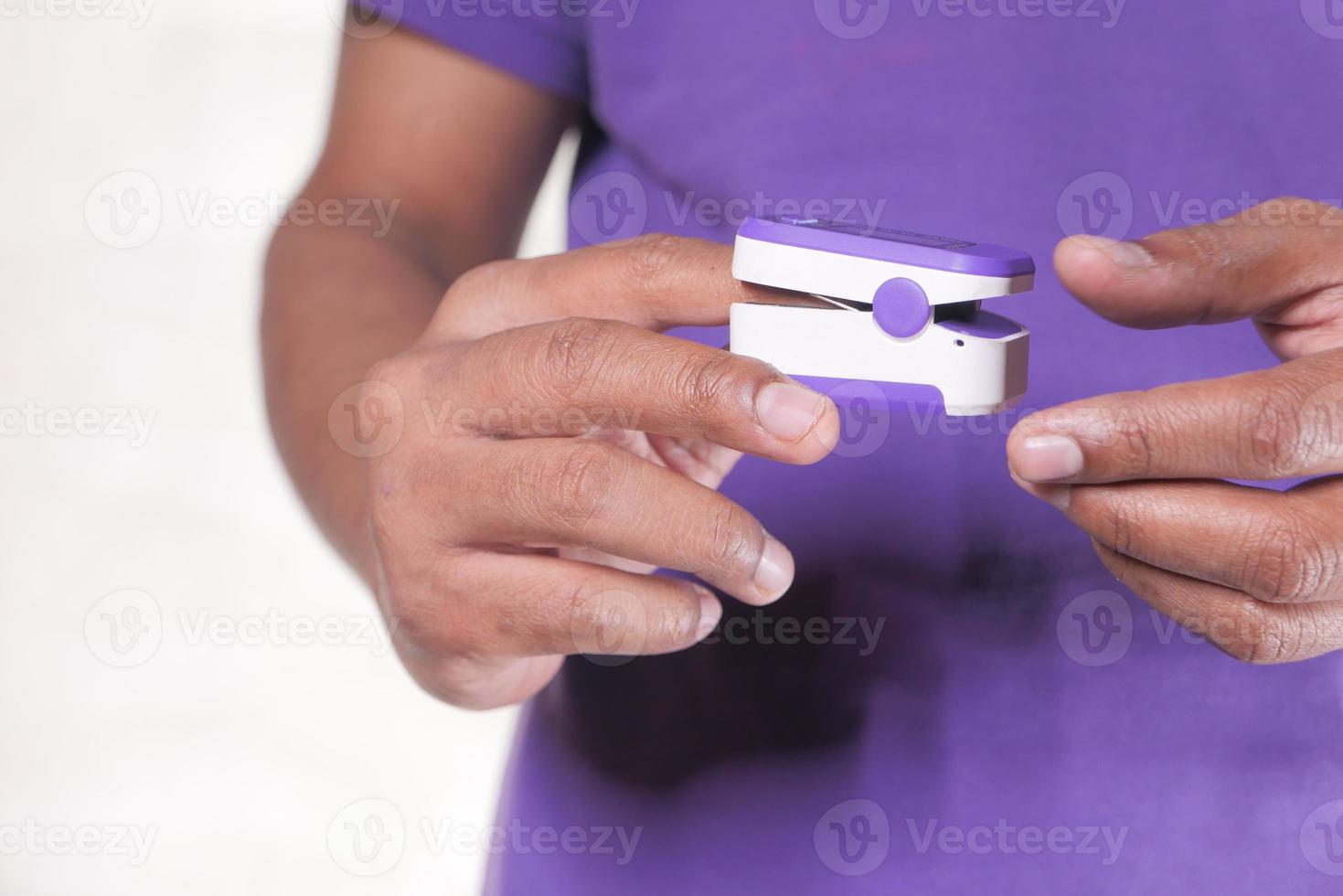 Hand des jungen Mannes mit einem Pulsoximeter foto