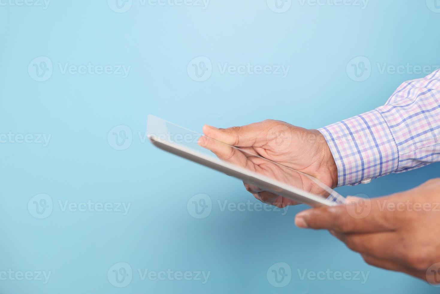 Geschäftsmann, der digitales Tablett auf blauem Hintergrund verwendet foto