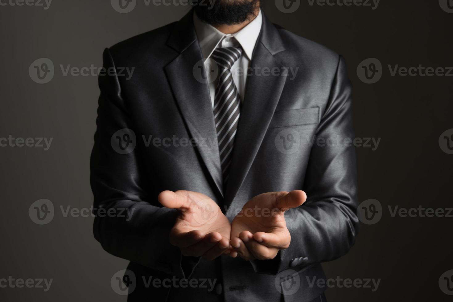 junger Geschäftsmann, der einen auf schwarzem Hintergrund isolierten Copyspace präsentiert foto