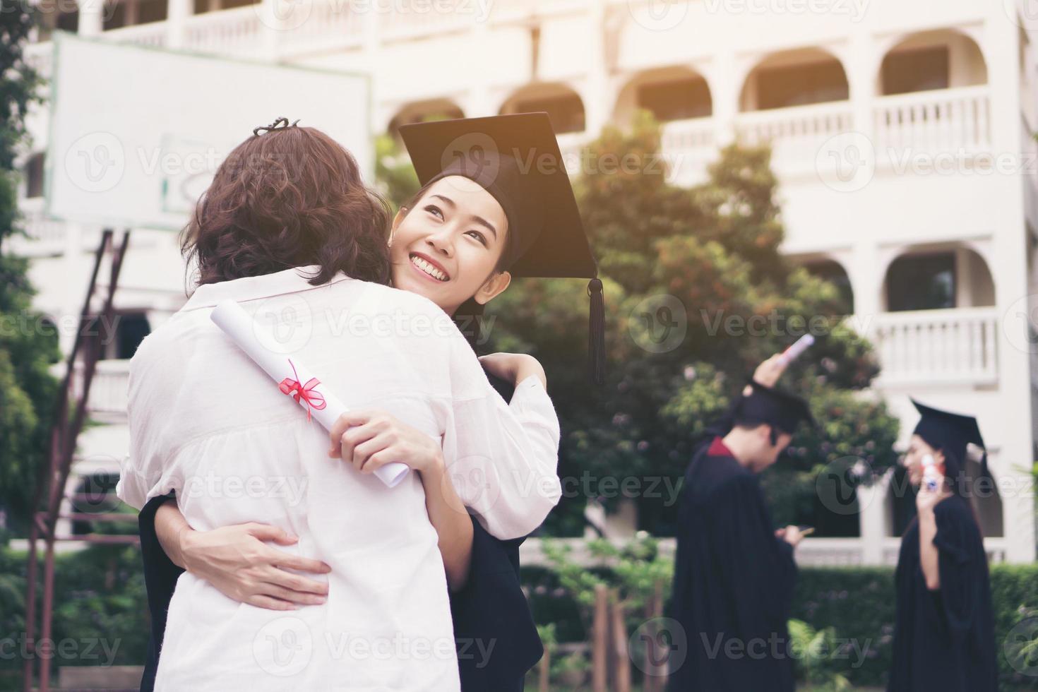 junge Absolventin, die ihre Mutter bei der Abschlussfeier umarmt foto