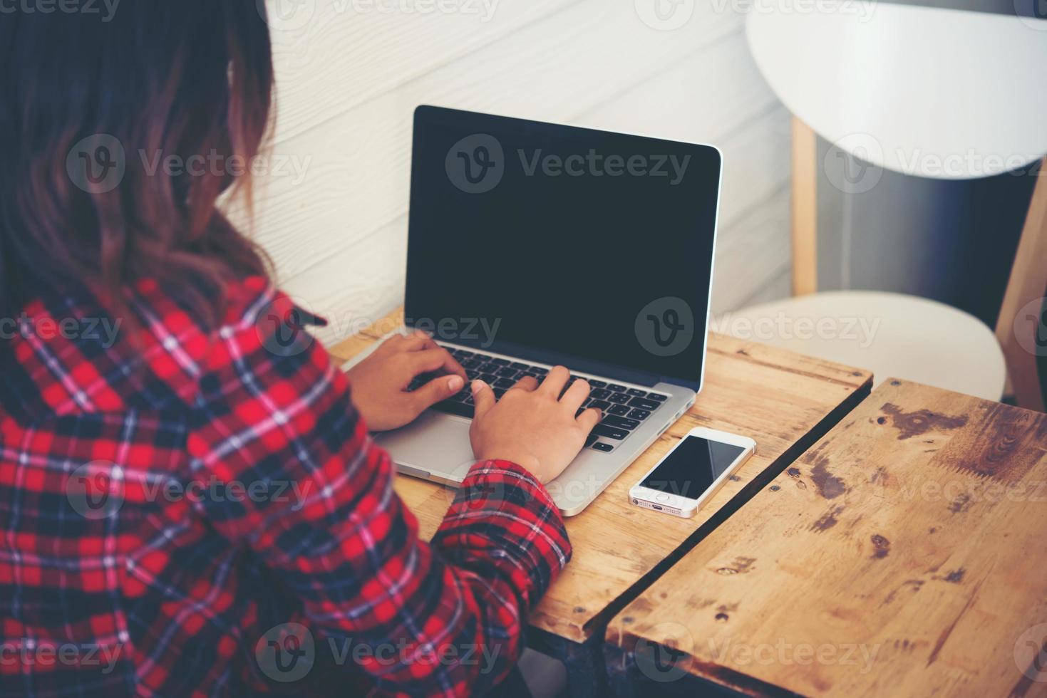 Nahaufnahme einer jungen Hipster-Frau, die einen Laptop während einer Kaffeepause benutzt foto