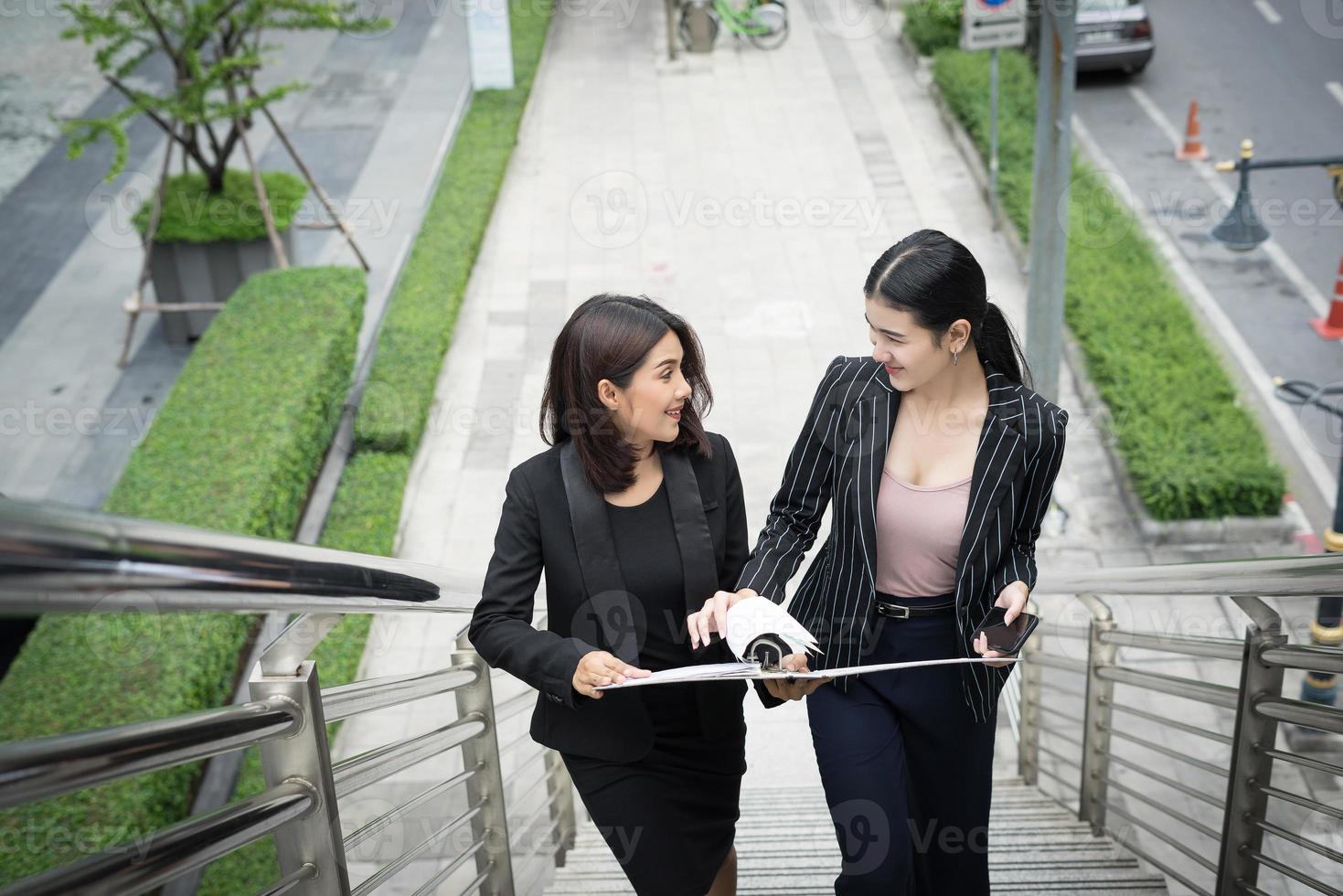 junge asiatische Geschäftsfrauen mit Dokumenten, die auf Treppen gehen foto