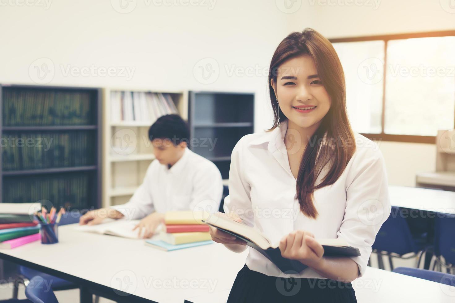 junge asiatische Studenten in der Bibliothek lesen ein Buch foto