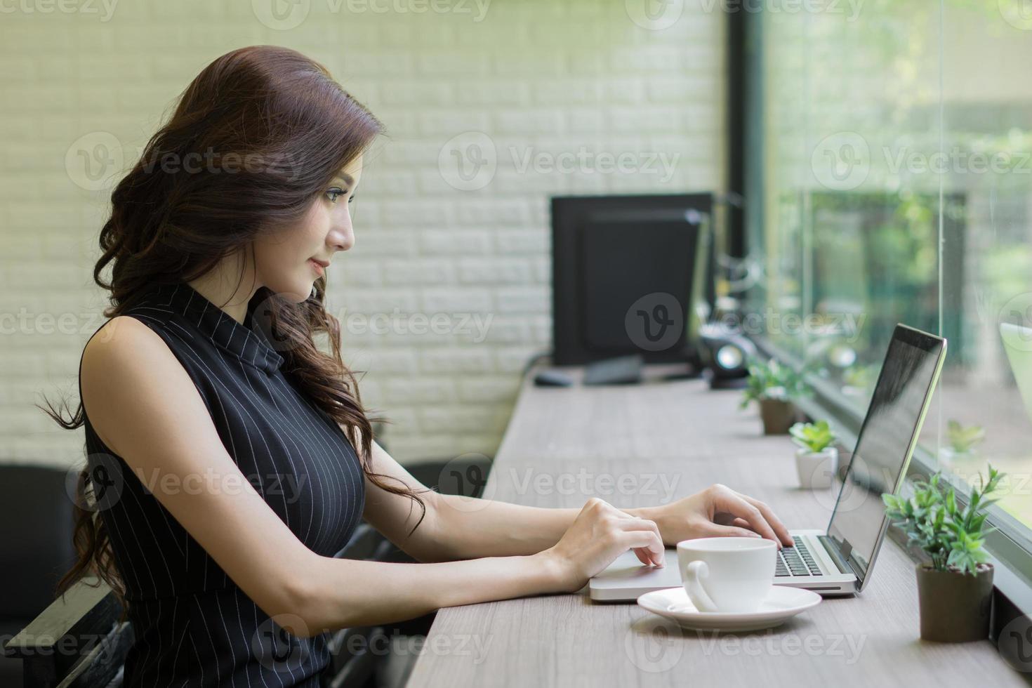 junge Geschäftsfrau, die am Laptop im Büro arbeitet foto