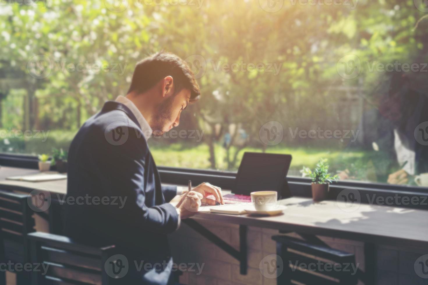 junger Geschäftsmann, der einen Anzug trägt und Laptop in einem Café benutzt foto