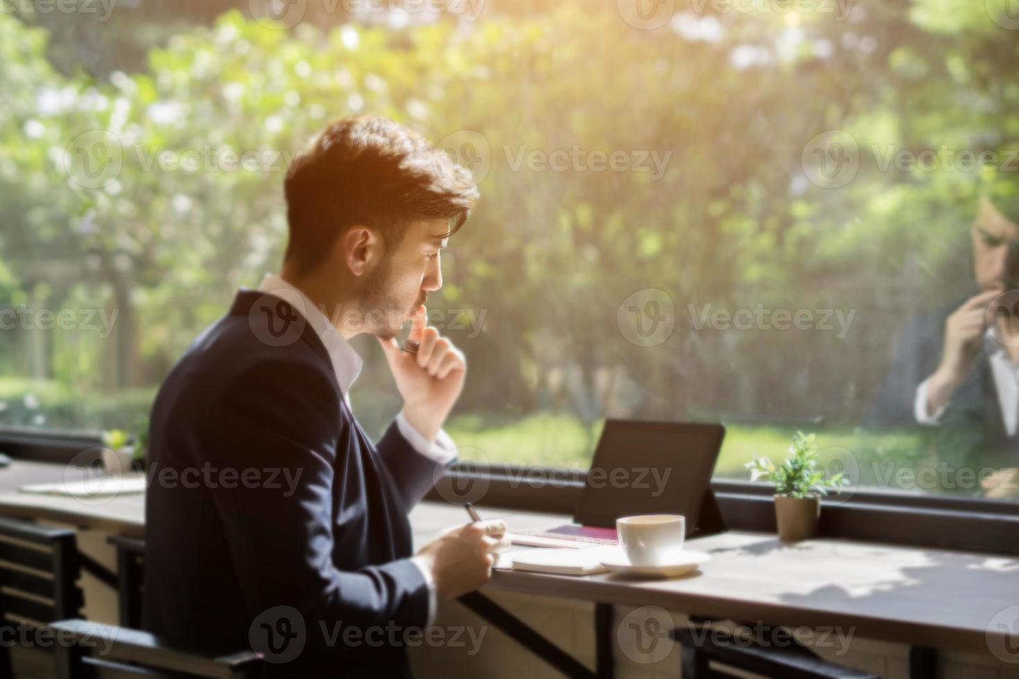 junger Geschäftsmann, der einen Anzug trägt und Laptop in einem Café benutzt foto