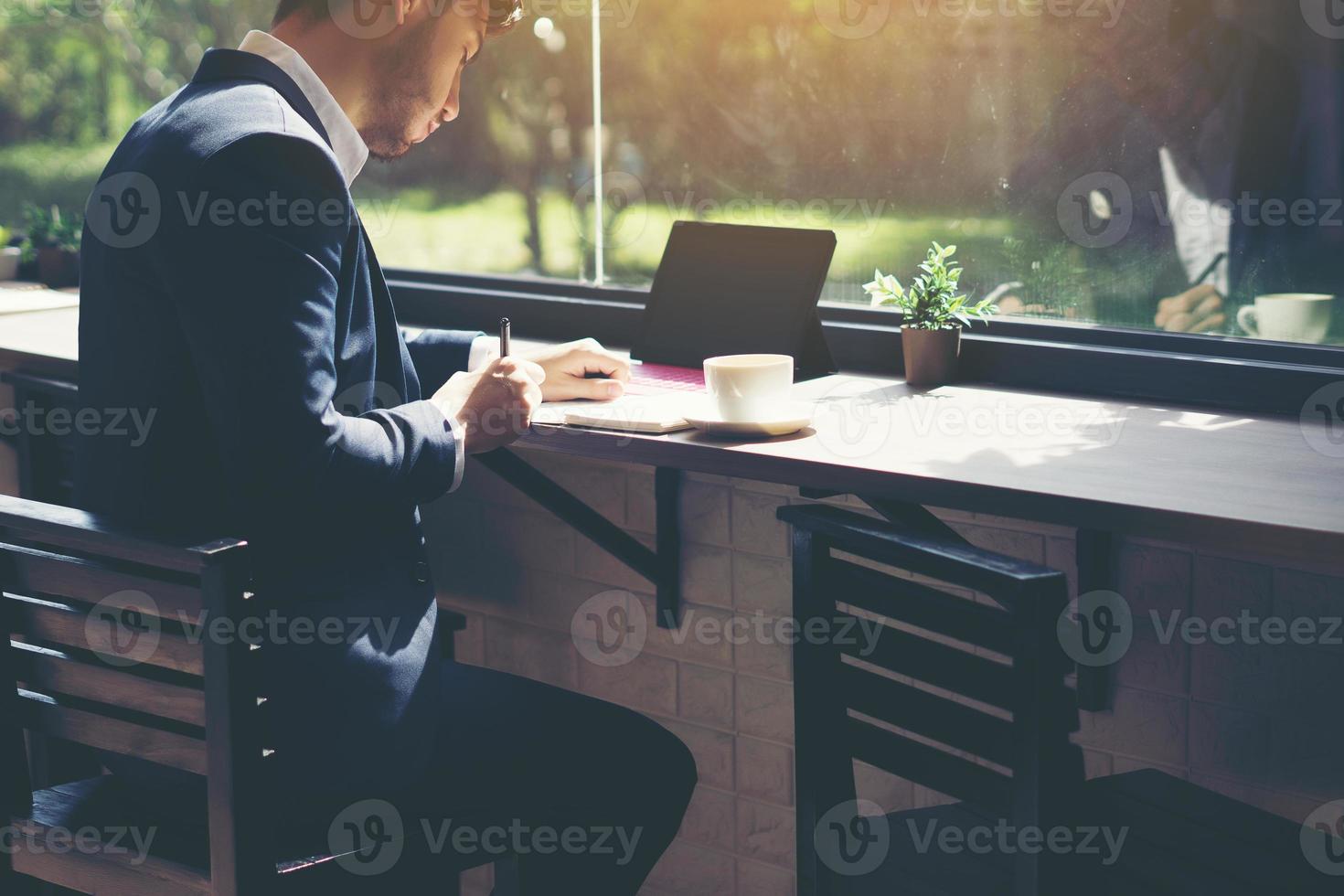 junger Geschäftsmann, der einen Anzug trägt und Laptop in einem Café benutzt foto