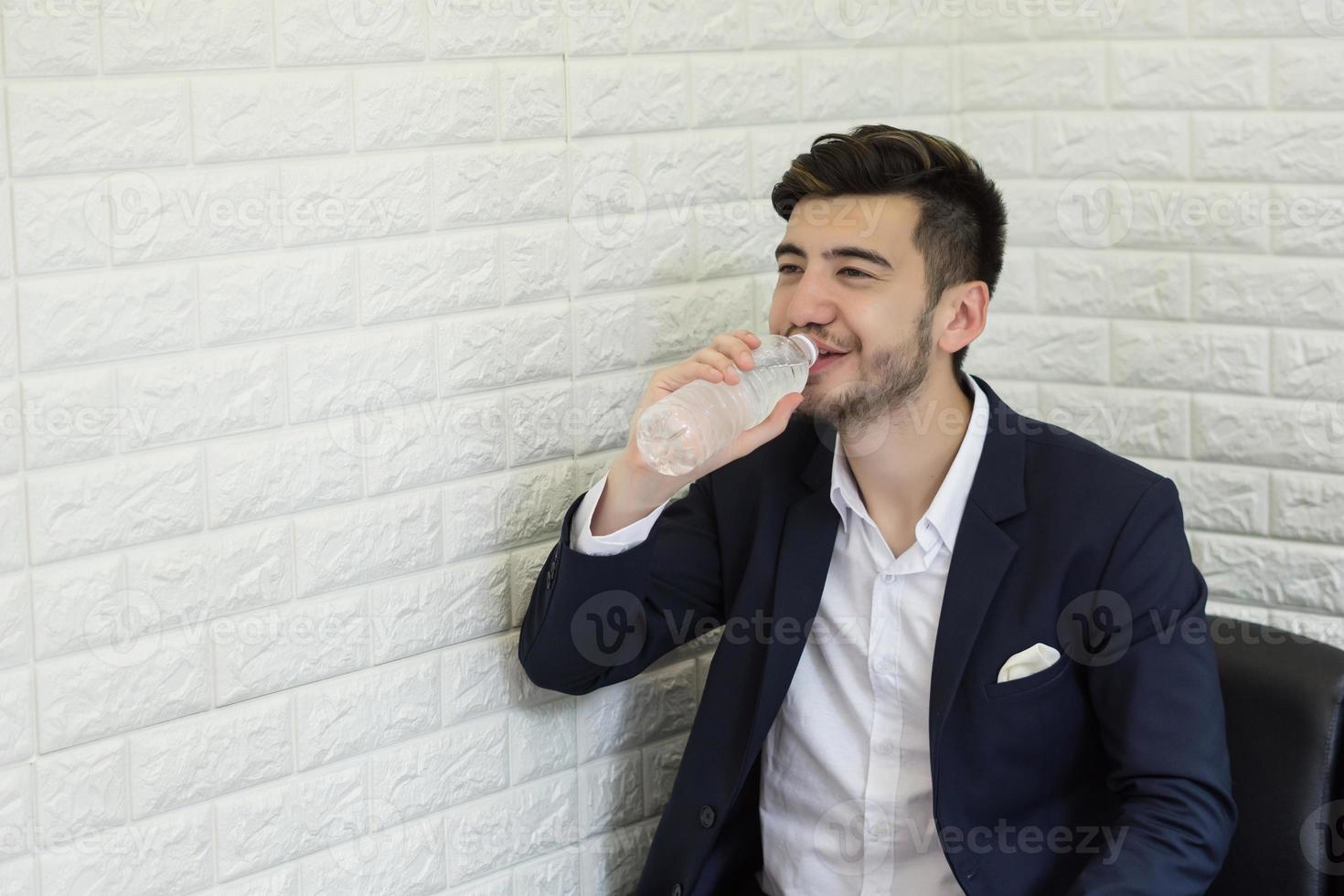 Trinkwasser des jungen Geschäftsmannes im Büro foto