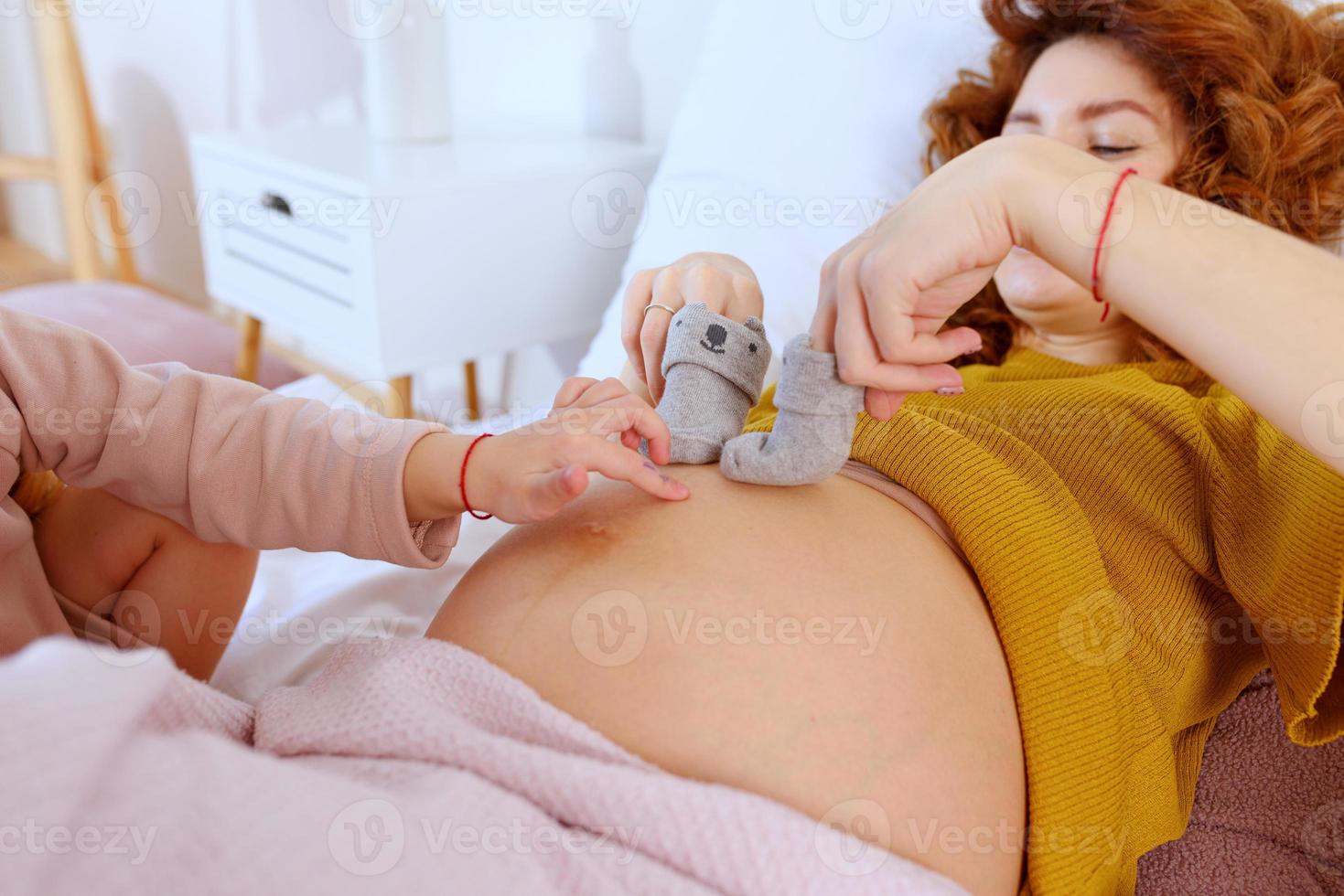 schwanger Mama Theaterstücke mit ihr Tochter. Konzept von Familie, Freude und Schwangerschaft foto