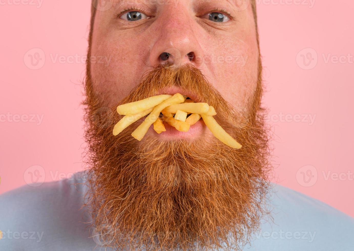 hungrig Mann mit Bart und Tätowierungen isst gebraten Kartoffeln foto