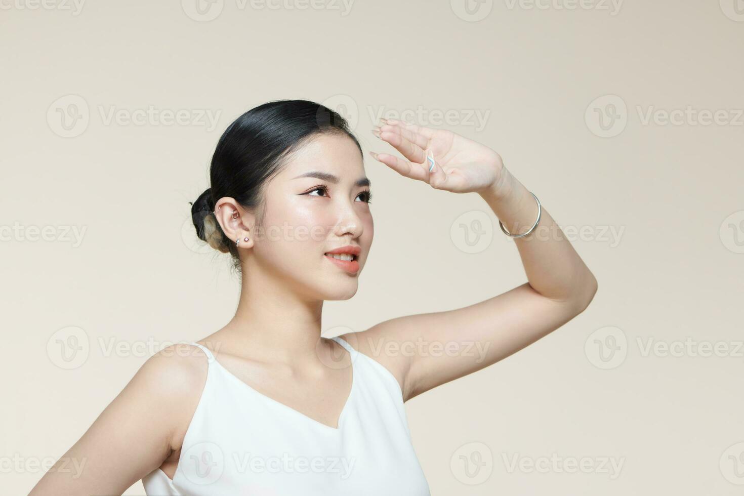 jung asiatisch Frau Abdeckungen ihr Gesicht von das Sonne mit Palme gegen ein Beige Hintergrund foto
