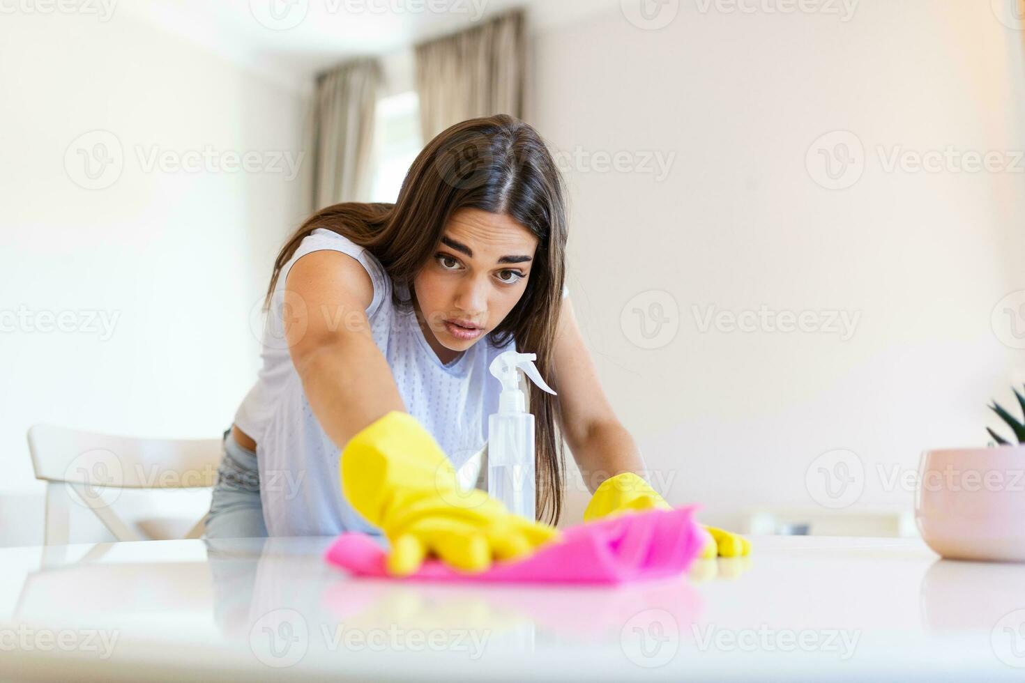 Schuss von ein jung Frau suchen müde während Reinigung beim heim. müde jung Frau Stehen mit Reinigung Produkte und Ausrüstung, Hausarbeit Konzept. foto